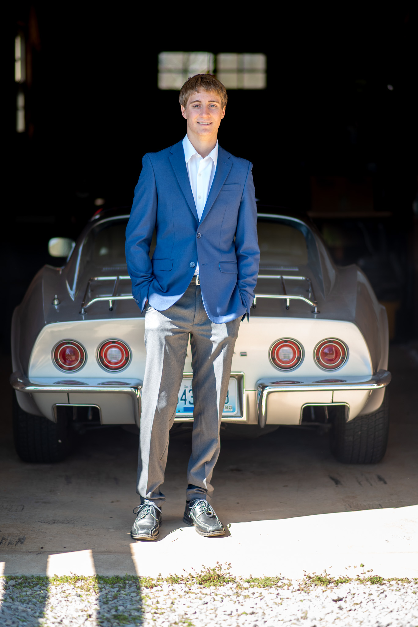 A senior portrait of a young man standing in front of his favorite sports car.