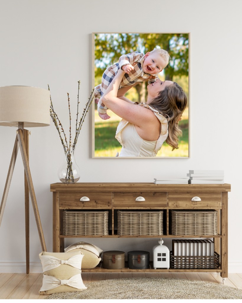A 16x20 portrait of a mother holding up her smiling child hangs on the wall above an entryway table.